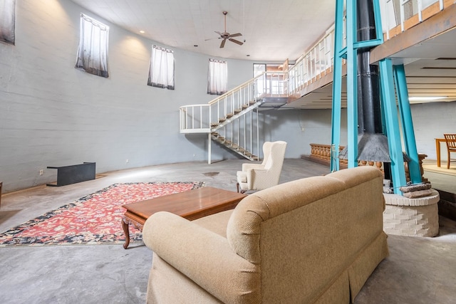 living room with ceiling fan, a high ceiling, a wealth of natural light, and concrete floors