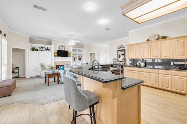 5502 Sundance Ct, Midland, TX 79707 - kitchen featuring light brown cabinets, a breakfast bar, crown molding, open floor plan, and a ceiling fan