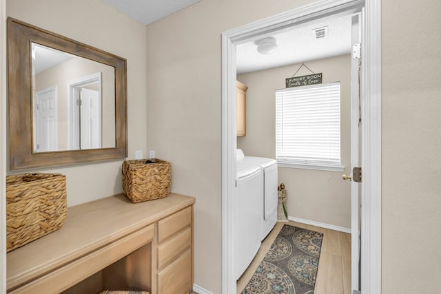 5502 Sundance Ct, Midland, TX 79707 - laundry area featuring cabinet space, independent washer and dryer, baseboards, and light wood-style floors