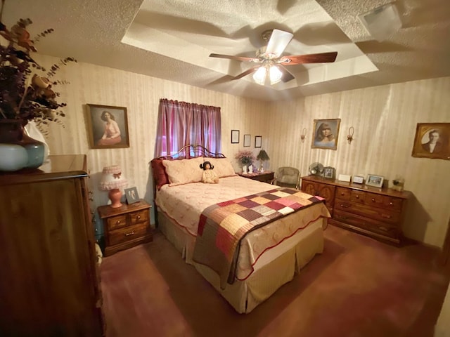 carpeted bedroom with ceiling fan, a raised ceiling, and a textured ceiling