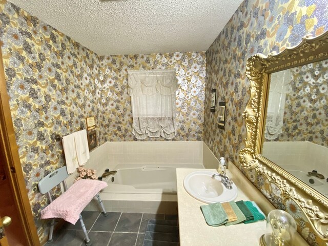 bathroom with tile patterned floors, a tub, vanity, and a textured ceiling