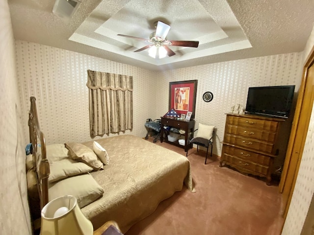 carpeted bedroom with a tray ceiling, ceiling fan, and a textured ceiling