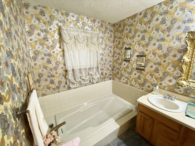 bathroom with vanity, a bathtub, and a textured ceiling