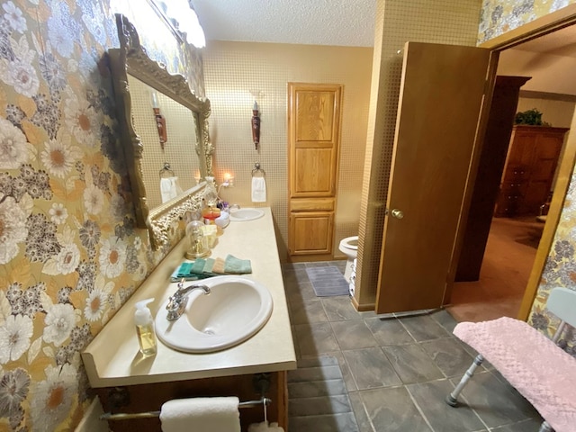 bathroom with tile patterned flooring, vanity, a textured ceiling, and toilet