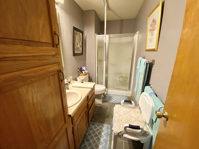 bathroom with vanity, tile patterned floors, toilet, a textured ceiling, and walk in shower