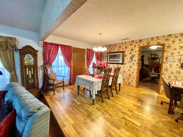 dining space featuring a textured ceiling, hardwood / wood-style flooring, and a notable chandelier