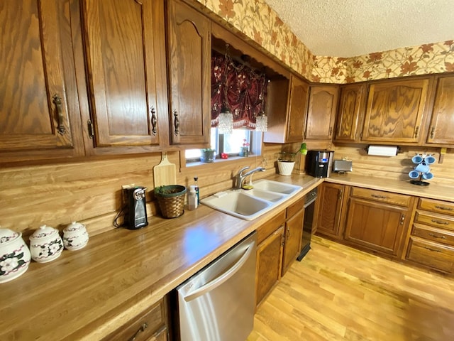 kitchen featuring dishwasher, sink, light hardwood / wood-style floors, and a textured ceiling