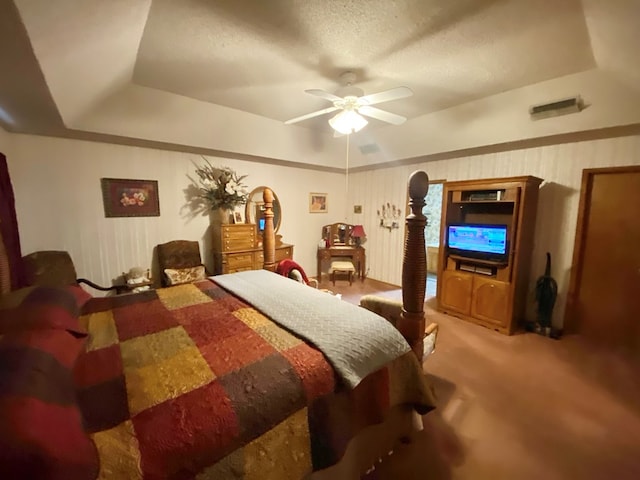 bedroom featuring carpet flooring, ceiling fan, a textured ceiling, and a tray ceiling