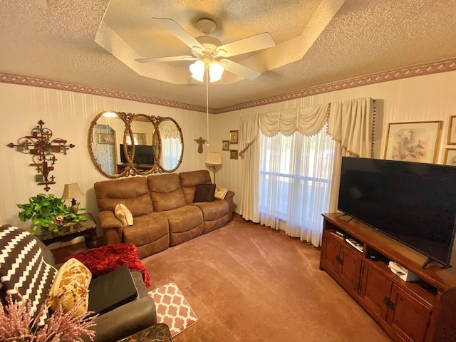 living room with a tray ceiling, ceiling fan, carpet floors, and a textured ceiling