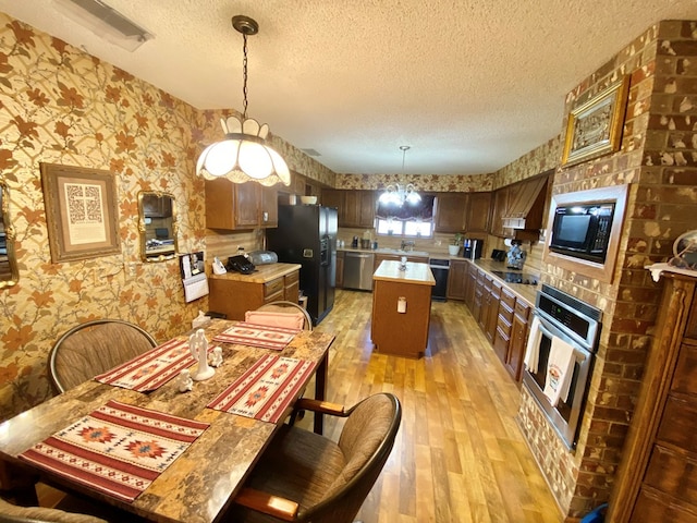 dining space with light hardwood / wood-style floors, sink, a textured ceiling, and a chandelier