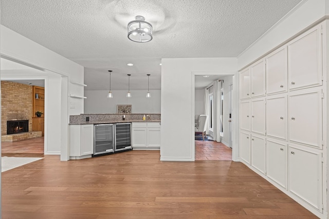 kitchen with white cabinetry, hanging light fixtures, light hardwood / wood-style flooring, and beverage cooler