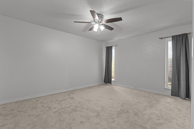 unfurnished room with ceiling fan, light colored carpet, and a textured ceiling