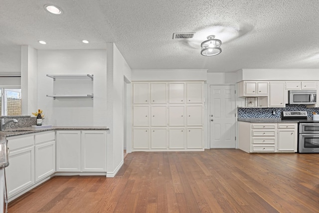 kitchen with sink, appliances with stainless steel finishes, dark hardwood / wood-style floors, tasteful backsplash, and white cabinets