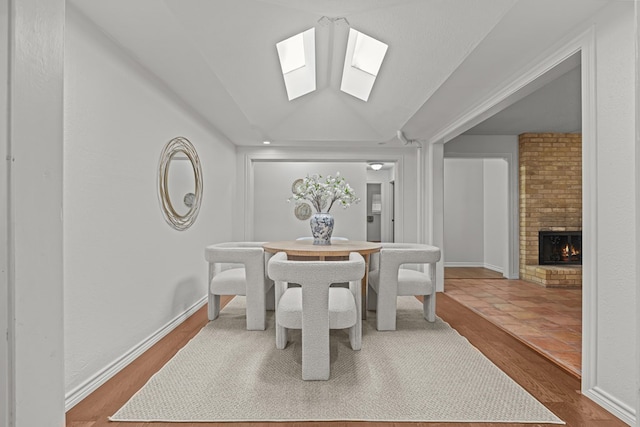 dining space featuring hardwood / wood-style flooring, a fireplace, and a skylight