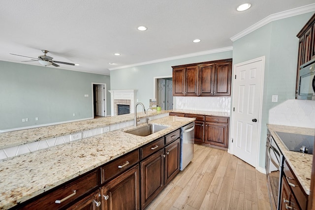 kitchen with light stone counters, appliances with stainless steel finishes, a fireplace, and sink