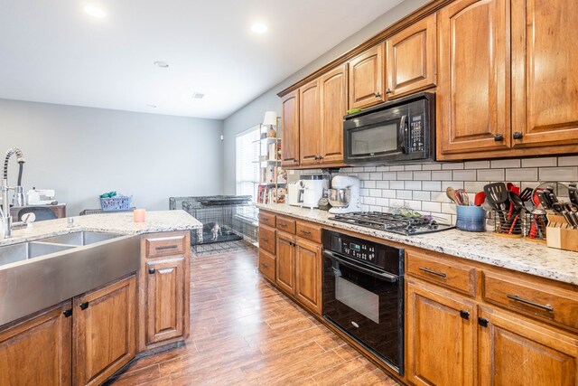 3505 Coquina Ln, Midland, TX 79707 - kitchen with black appliances, light wood-style floors, tasteful backsplash, a sink, and light stone countertops
