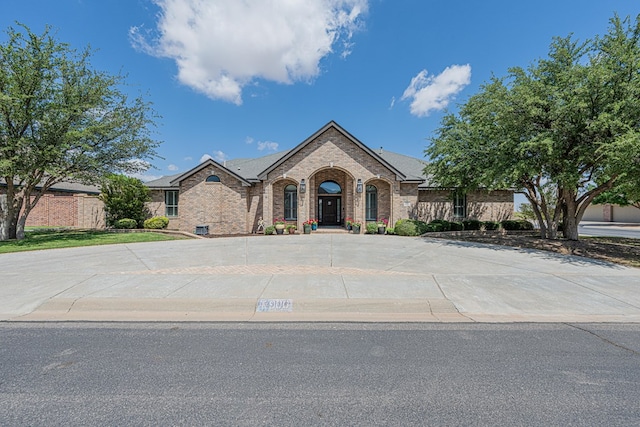 view of front of house featuring fence, curved driveway, and brick siding