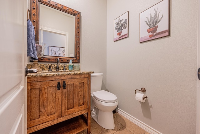 bathroom with vanity, tile patterned flooring, baseboards, and toilet