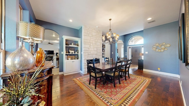 dining space with ceiling fan with notable chandelier, arched walkways, dark wood-type flooring, and visible vents