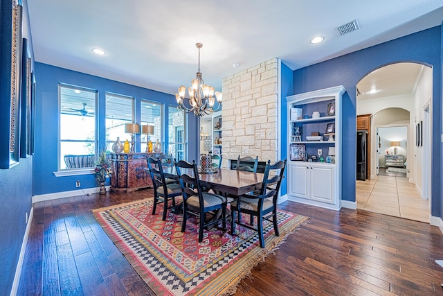 dining space with an inviting chandelier, wood-type flooring, arched walkways, baseboards, and visible vents