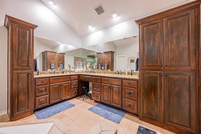 bathroom with a sink, double vanity, a bathtub, lofted ceiling, and visible vents