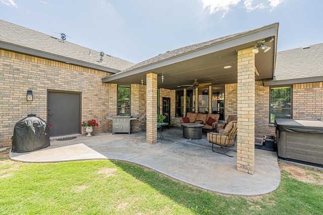 view of patio / terrace with a hot tub, a ceiling fan, and an outdoor fire pit