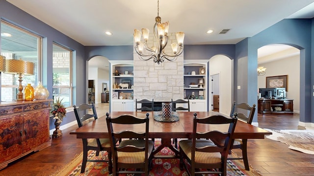 dining space featuring arched walkways, an inviting chandelier, wood finished floors, and visible vents
