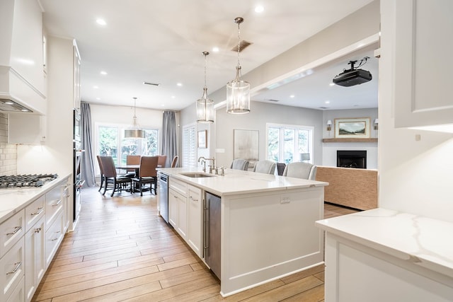 15 Lakes Dr, Midland, TX 79705 - kitchen featuring appliances with stainless steel finishes, light wood-type flooring, white cabinetry, open floor plan, and a center island with sink