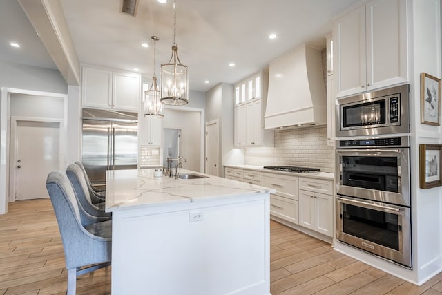 15 Lakes Dr, Midland, TX 79705 - kitchen with custom range hood, built in appliances, light wood-style flooring, tasteful backsplash, and recessed lighting
