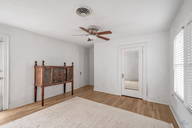 bedroom featuring ceiling fan, multiple windows, and light hardwood / wood-style flooring