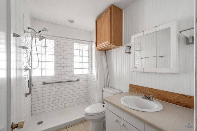 bathroom with toilet, vanity, tile patterned flooring, and tiled shower