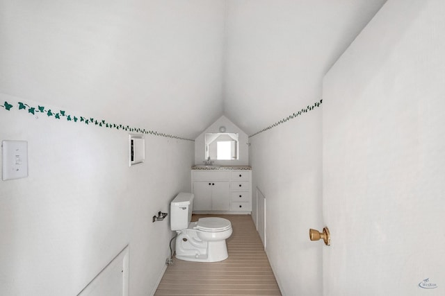 bathroom with lofted ceiling, toilet, and hardwood / wood-style flooring