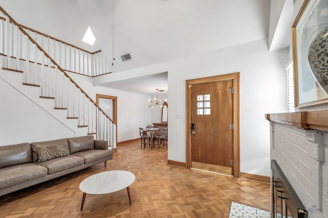 living room featuring a high ceiling, plenty of natural light, a notable chandelier, and light parquet flooring