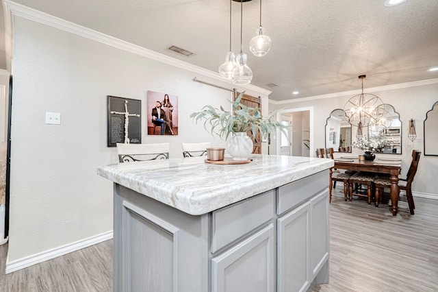 kitchen with visible vents, crown molding, baseboards, a center island, and light wood-style flooring