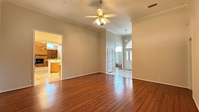 4804 Bishops Castle Dr, Midland, TX 79705 - spare room featuring ceiling fan, a large fireplace, wood finished floors, and crown molding