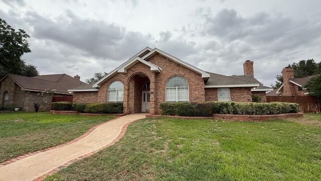 4804 Bishops Castle Dr, Midland, TX 79705 - view of front of property with brick siding, a front yard, and a chimney
