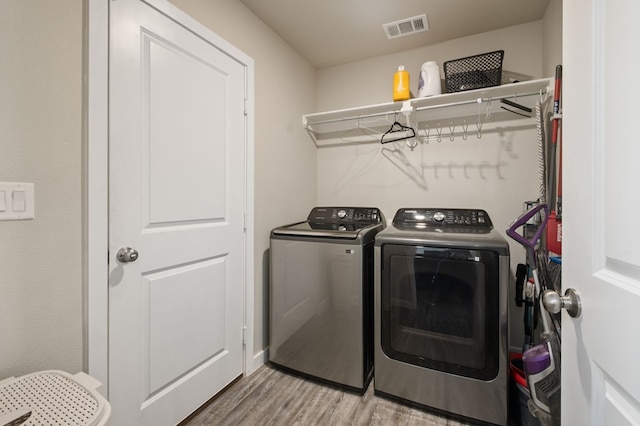 laundry area with washing machine and clothes dryer, laundry area, wood finished floors, and visible vents