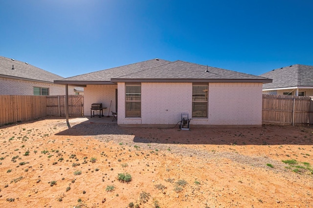 back of house featuring brick siding, a fenced backyard, and a patio
