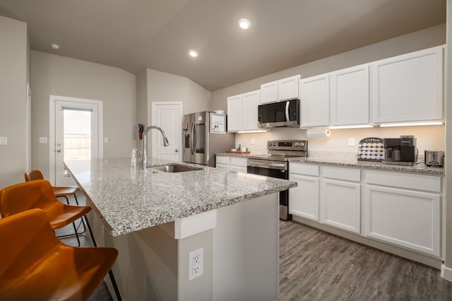 kitchen with a sink, white cabinets, lofted ceiling, a breakfast bar, and stainless steel appliances