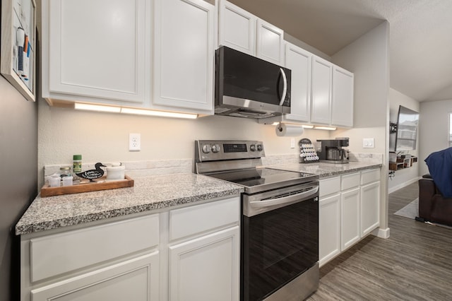 kitchen with light stone countertops, wood finished floors, baseboards, stainless steel appliances, and white cabinetry