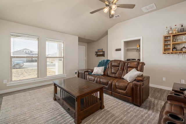 living area featuring visible vents, a ceiling fan, baseboards, and vaulted ceiling