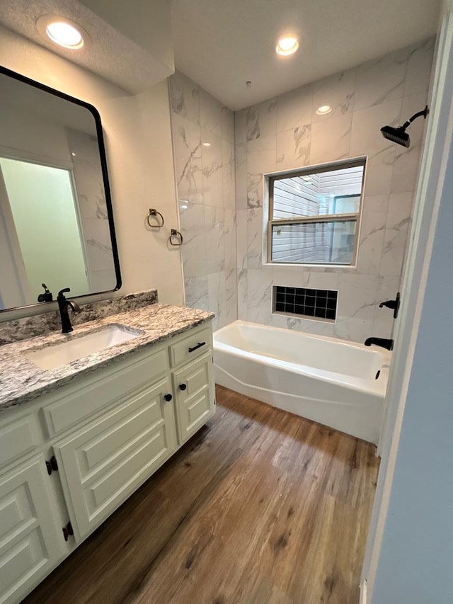 bathroom with tub / shower combination, recessed lighting, wood finished floors, and vanity