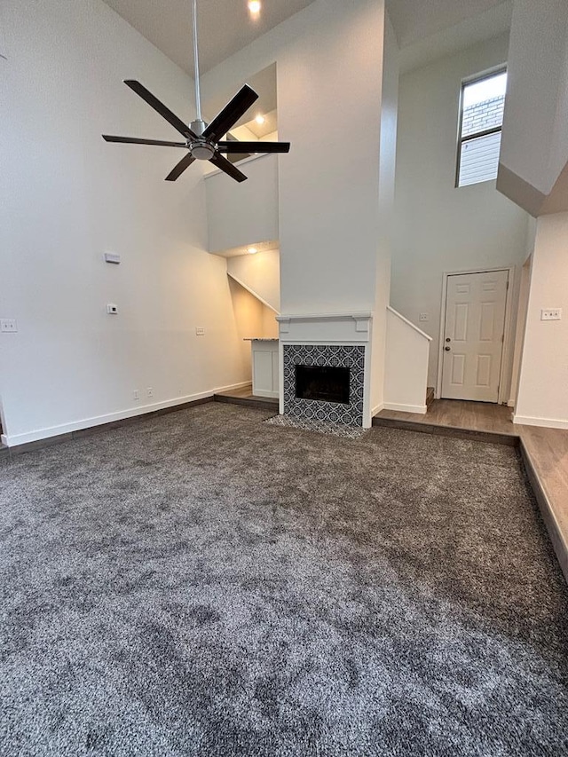 unfurnished living room with a fireplace, baseboards, a towering ceiling, and ceiling fan