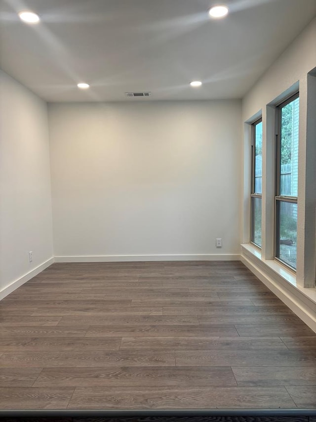 empty room featuring visible vents, baseboards, and dark wood-style floors