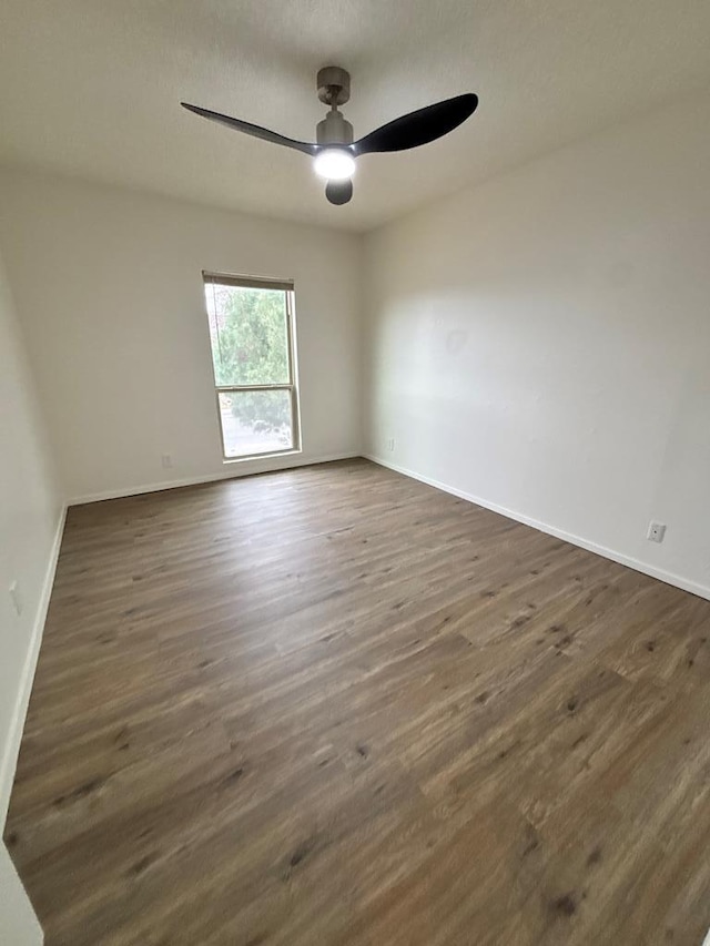 unfurnished room featuring baseboards, ceiling fan, and dark wood-style flooring