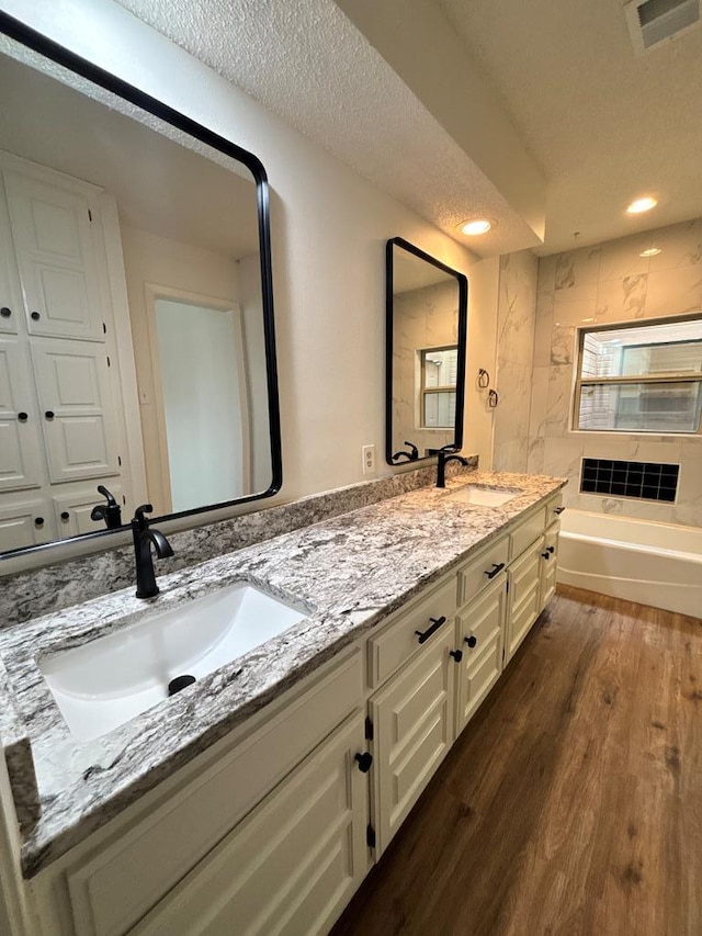 bathroom with a sink, visible vents, a textured ceiling, and wood finished floors