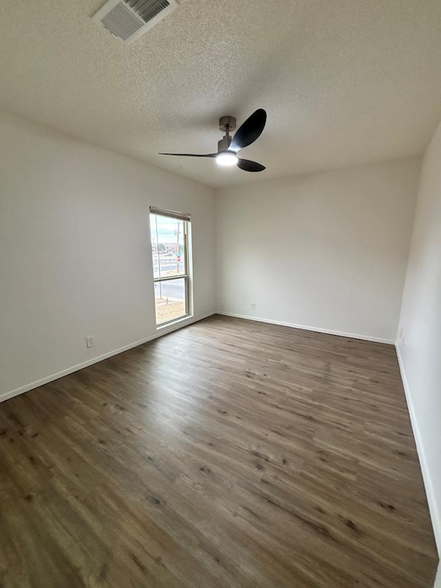 unfurnished room with visible vents, baseboards, ceiling fan, dark wood-style floors, and a textured ceiling