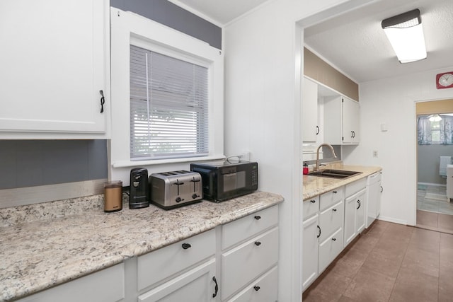 601 E 1st St, Coleman, TX 76834 - kitchen featuring black microwave, white cabinets, tile patterned flooring, dishwasher, and light stone counters