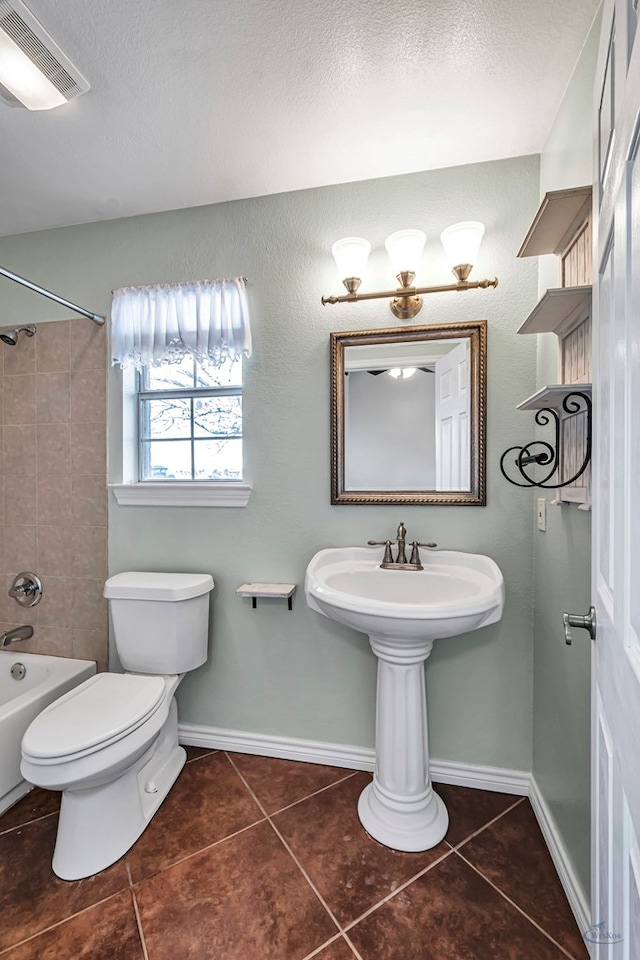 bathroom with tiled shower / bath combo, tile patterned floors, toilet, and a textured ceiling