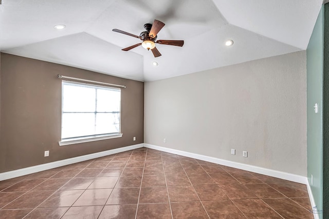 empty room featuring lofted ceiling, dark tile patterned flooring, and ceiling fan